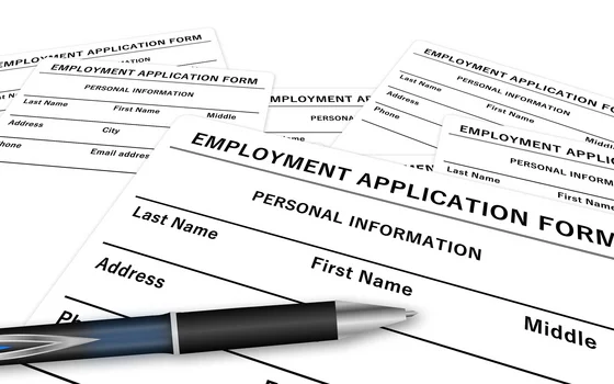 The image shows multiple employment application forms with sections for personal information such as last name, first name, middle name, address, phone number, and email address. A pen is placed on top of the forms, indicating readiness to fill them out.